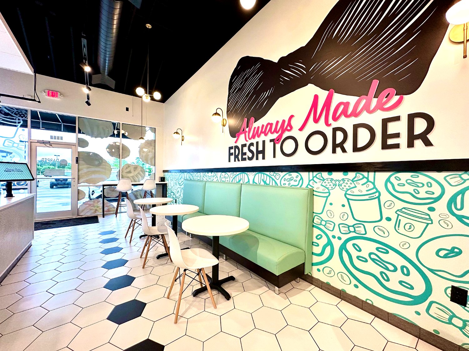 Dapper Doughnut seating area with mint booths, hex-tile floor and the Always Made Fresh to Order mural